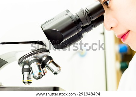 Asian Researcher looking through a Microscope Lens in a Biochemistry Lab
