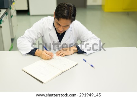 Handsome Researcher writing on his Lab-book in Chemistry Lab