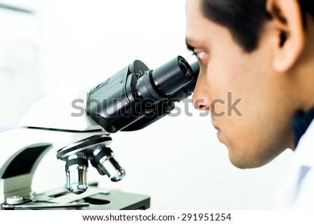 A concentrated Researcher working with a Microscope in a Biochemistry Lab