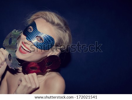 Smiling blonde beauty wearing carnival mask, looking at camera.