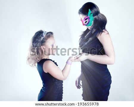 Two beautiful young girls looking at bright diamond. Studio shot.