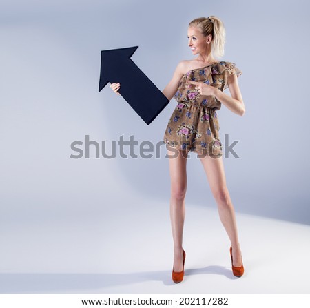 Full length photo of beautiful sexy blonde woman holding black empty arrow. Girl with toothy smile and slim body. Studio photo.