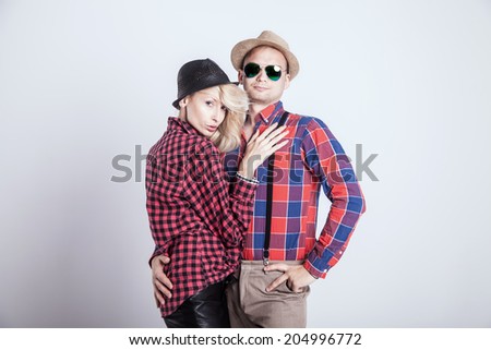 Beautiful blonde young woman posing with handsome man wearing hat, smiling.