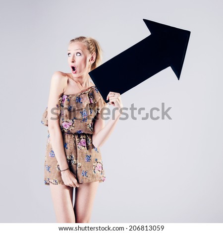 Full length photo of beautiful sexy blonde woman holding black empty arrow. Girl with slim body. Studio photo.