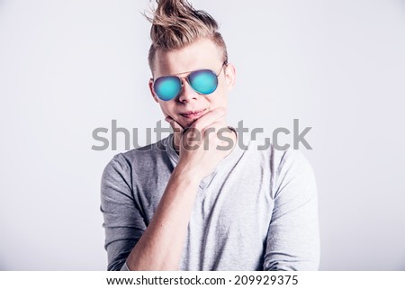 Handsome young man posing in creative hairstyle and sunglasses