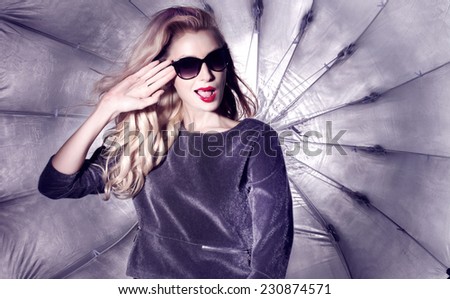 Smiling happy blonde woman wearing fashionable sunglasses, studio photo.