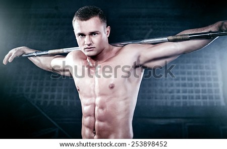 Muscled handsome man posing in studio, looking at camera.