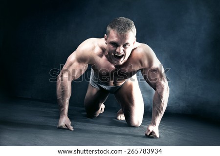 Angry muscular man kneeling, shouting.