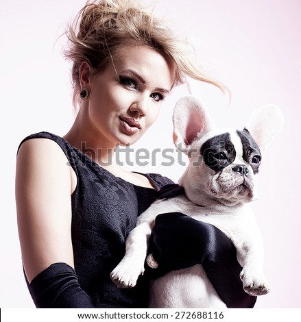 Elegant beautiful blonde woman posing with pug dog over pink background.