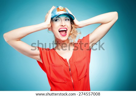 Portrait of sexy blonde woman with curly hair. Girl wearing cap. Blue background.