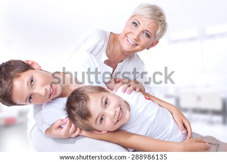 Family portrait. Smiling beautiful mother playing with two sons, looking at camera. Happy people.