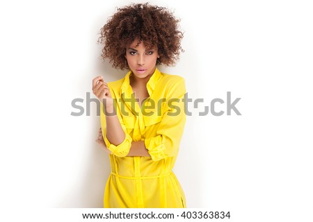Portrait of beautiful young African American woman with afro and glamour makeup. Studio shot. Yellow fashionable dress.