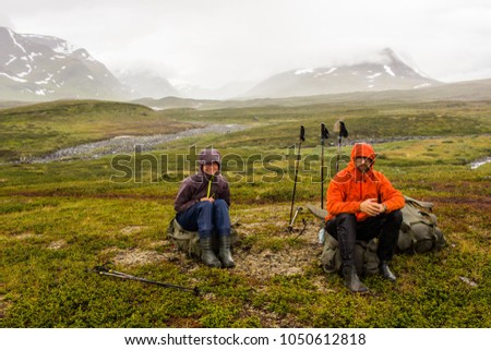 Couple resting after hard hiking day, with heavy backpacks in polar Sweden, but still happy