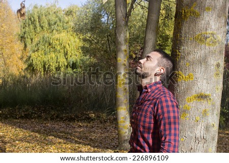Guy thinking something supported on a tree.