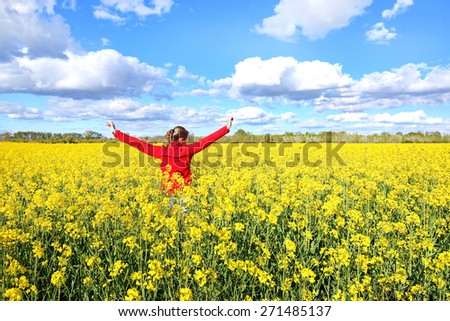 Happy woman running through a colza field.