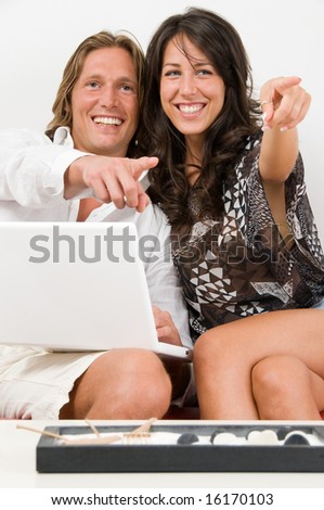 Young couple on the sofa play with the laptop