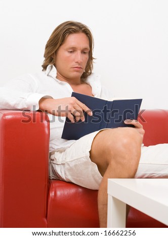 young man reads a book relaxed on the sofa
