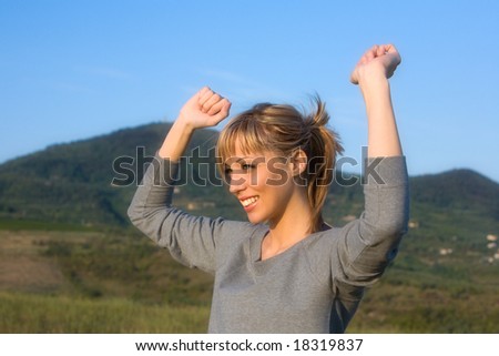 Young smiling woman spreading arms to  blue sky