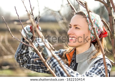 Happy gardener woman using pruning scissors in orchard garden. Pretty female worker portrait with pruners
