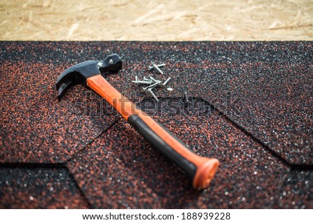 Shingle roof.  Asphalt shingles on a roof of wood with hammer and nails. selective focus