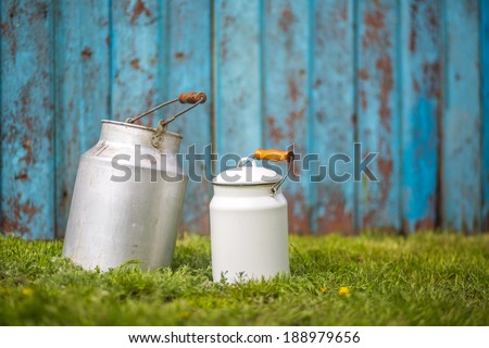 Rural background with vintage milk cans over grass and blue wooden background