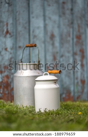 Milk cans on wood vintage background. toned image, focus on white can