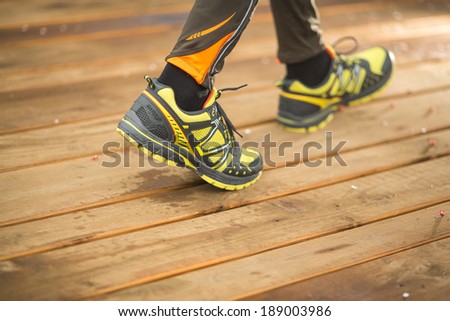 Feet of jogging person on wooden bridge in motion. focus on right shoe