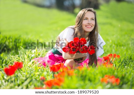Portrait of beautiful smiling young woman with summer flowers against background of summer green park. Summer, spring joy concept. copy space