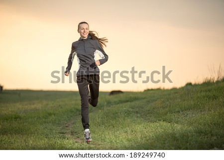 Running woman. Runner jogging over sunset sky. Female fitness model training outside in motion focus on face