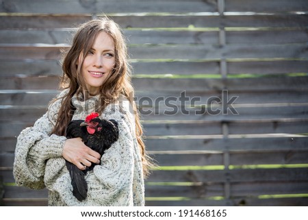 Natural young woman enjoy the beginning of new day with care of her domestic chicken. Simple rural life
