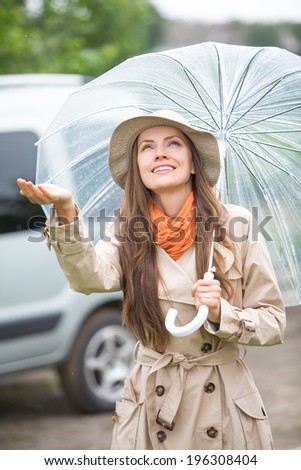 Autumn woman happy after rain walking with umbrella. Female model looking up at clearing sky joyful on rainy fall day in the street