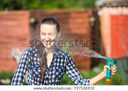 Summer garden, watering - beautiful woman watering lawn with garden hose in the garden