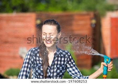 Beautiful young woman having fun in summer garden, woman working in the garden, watering plants