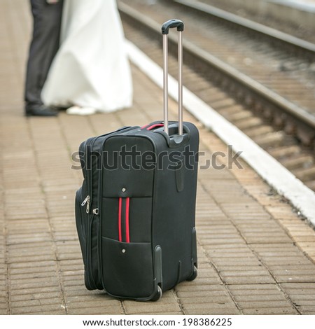 Vacation concept. Meeting. Suitcase and  couple kissing in the background at the railway station. daylight, focus on suitcase