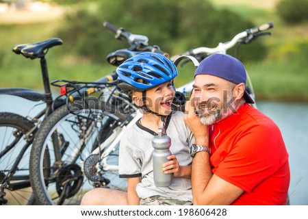 Carefree family, father and son having fun outdoors after riding bikes. Music, MP3, fun, sport and active life concept