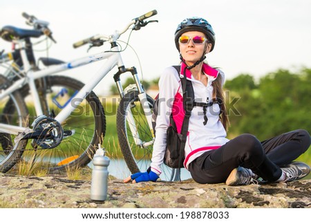 Beautiful sport smiling girl sitting next to bike, summer time