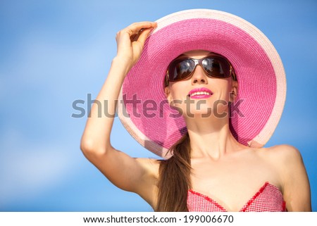 Beautiful woman in hat and sunglasses. Fashion woman in hat over blue sky background