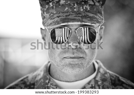 Proud us army soldier with american flag in sunglasses reflection. black and white