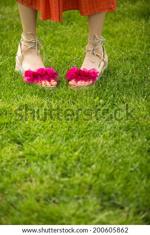 Green grass and woman legs in funny summer sandals. Summer vacation concept
