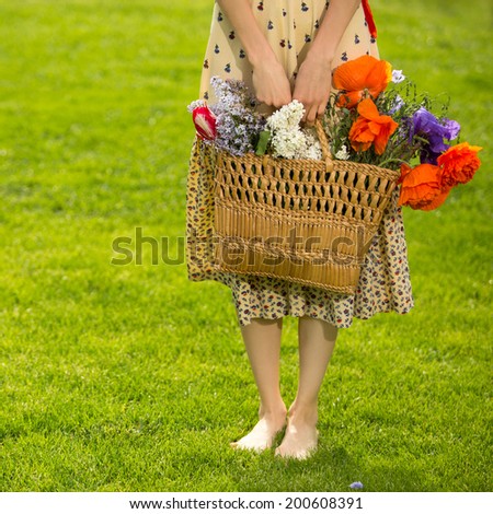 Picture of young woman with basket full of flowers. focus on hands and basket with flowers