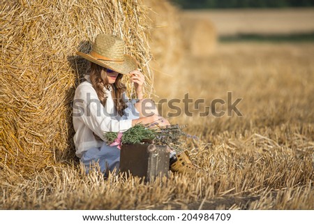 Fashion woman with suitcase at autumn field. Beauty autumn woman dreaming with hat hide face