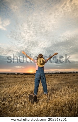 Young girl spreading hands with joy and inspiration facing the sun. Happy woman with hands up on sunset background. grain added