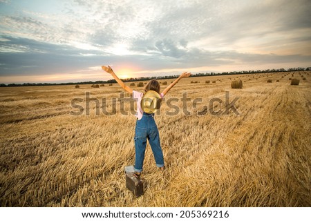 Young girl spreading hands with joy and inspiration facing the sun. Happy woman with hands up on sunset background