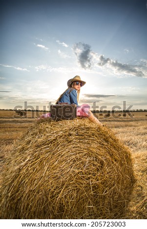 Happy traveler relaxing sitting on hay roll enjoying her journey and vacation