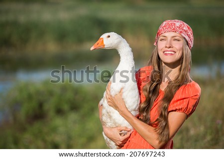 Young woman farmer holds goose happy smiling