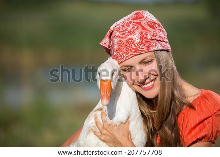 Beautiful woman hugs a goose. Concept of friendship between people and animal