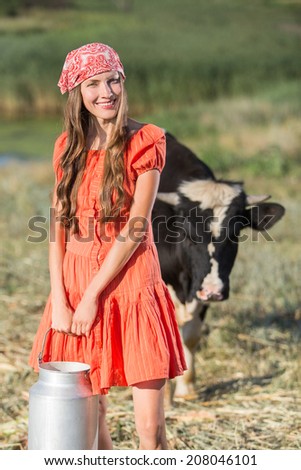 Smiling young farmer carrying fresh milk in a milk can
