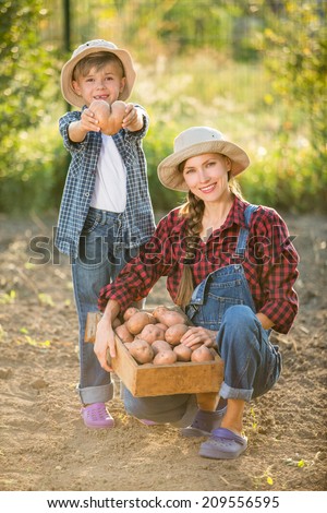 Gardening - happy mother with little son working in vegetable garden. focus on woman