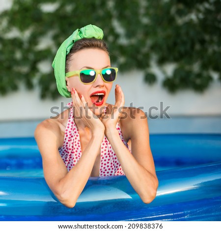 Beauty surprised retro woman. Beautiful young girl in retro look with red lips in retro swimsuit, sunglasses in swimming pool. copy space