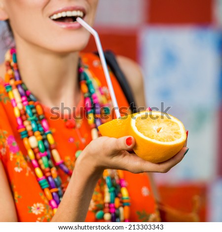 Fashion woman drinking orange juice smiling. focus on oranges and hand